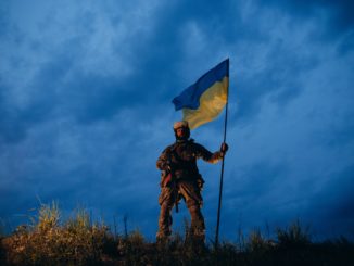 Armed Ukrainian warrior with blue and yellow flag in the evening